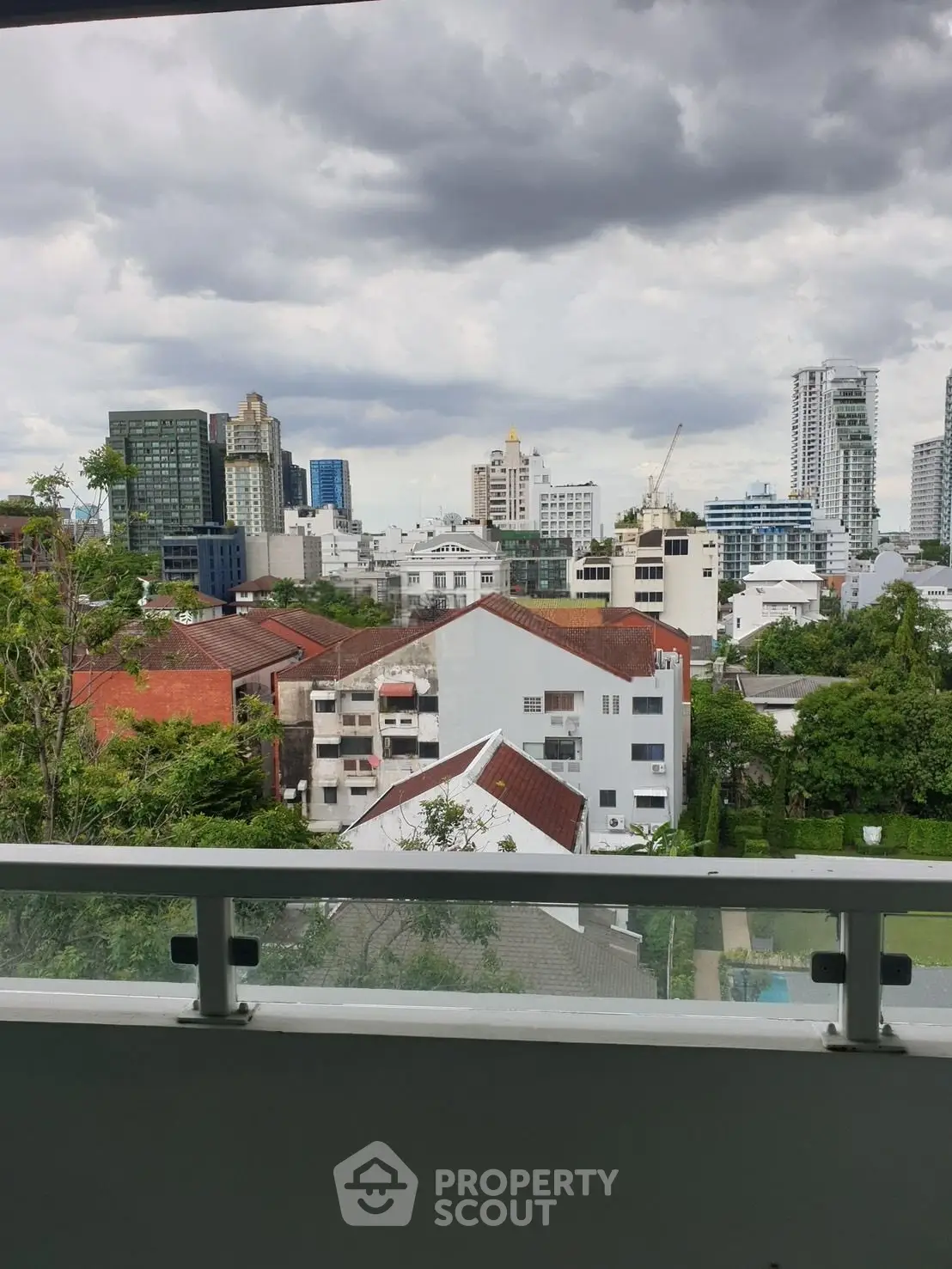Stunning cityscape view from a modern balcony, showcasing urban skyline and lush greenery.