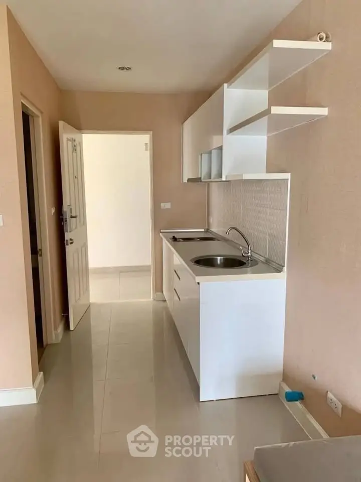 Compact kitchen with sleek white cabinets and modern fixtures in a cozy apartment setting.