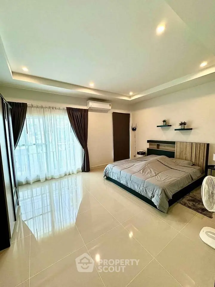 Spacious modern bedroom with large windows and elegant decor, perfect for relaxation and comfort.