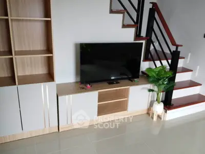 Modern living room with sleek TV stand and stylish staircase design.