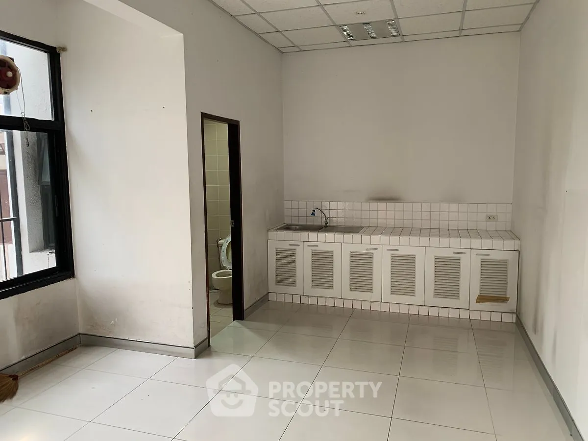 Spacious room with tiled floor and kitchenette, ideal for versatile use.