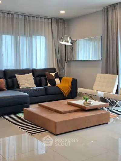 Modern living room with stylish furniture and elegant decor, featuring a sleek black sofa and contemporary lighting.