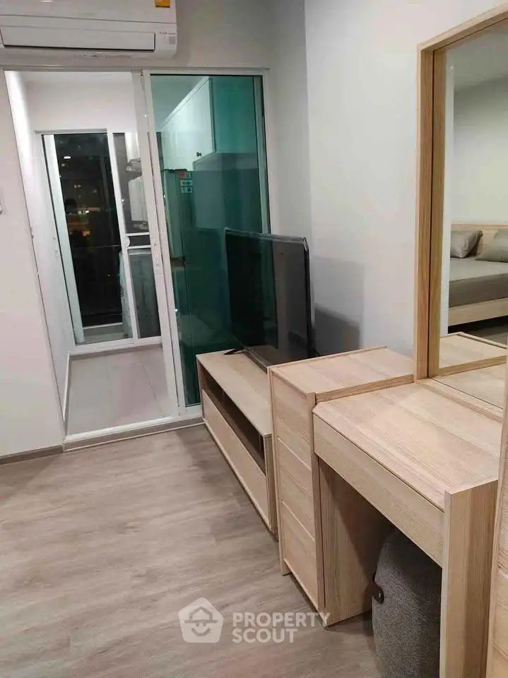 Modern apartment interior with sleek wooden furniture and sliding glass doors leading to a balcony.