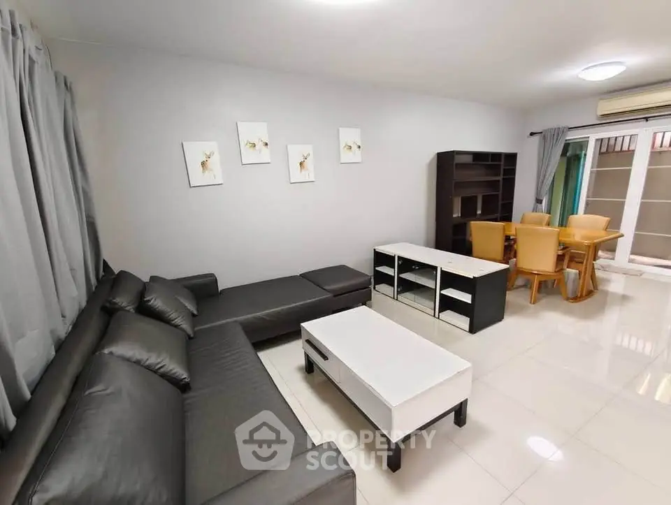 Spacious modern living room with sleek black sofa and elegant dining area