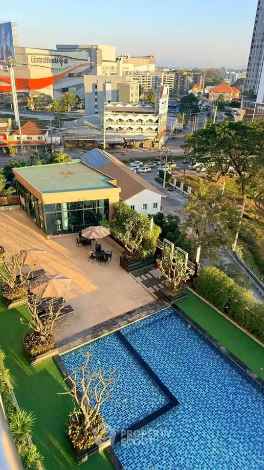 Stunning aerial view of a modern building with a luxurious pool and lush garden, perfect for urban living.