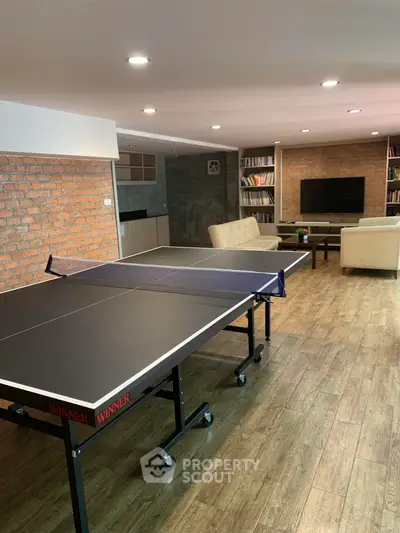 Spacious recreation room with ping pong table and cozy seating area, perfect for entertainment.