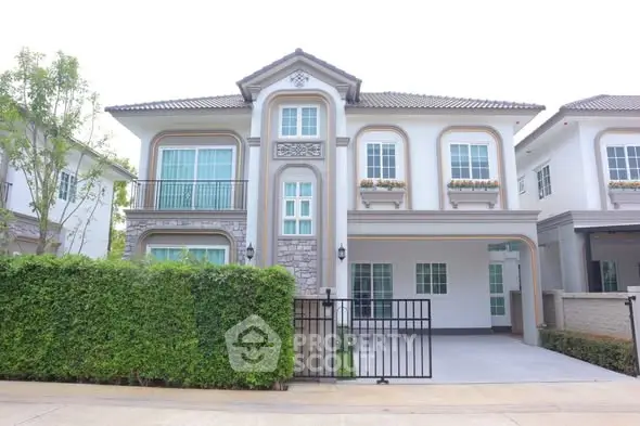 Elegant two-story house with gated driveway and lush greenery