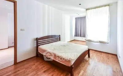 Spacious bedroom with wooden flooring and natural light