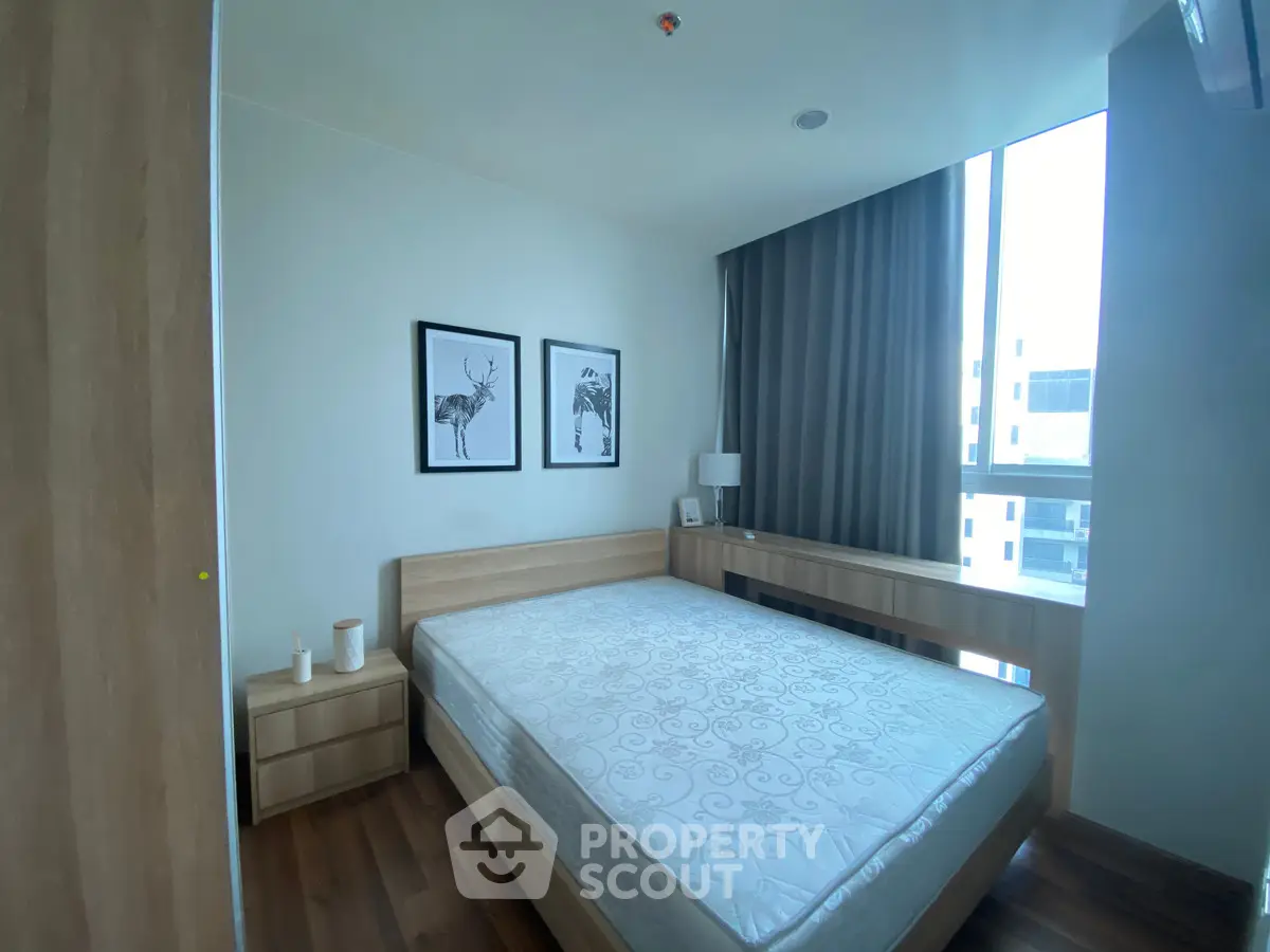 Modern bedroom with large window and stylish decor in a contemporary apartment.