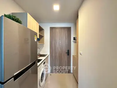 Modern compact kitchen with stainless steel fridge and washing machine