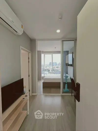 Modern apartment interior with bedroom and city view, featuring sleek design and natural light.