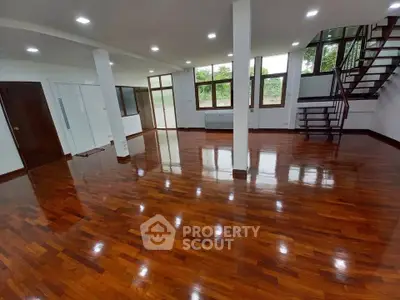 Spacious open-plan living area with polished wooden floors and modern staircase