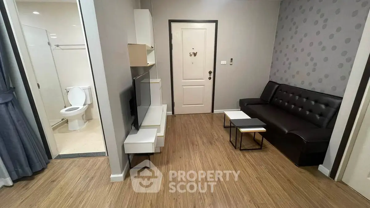Modern living room with sleek furniture and open view to bathroom, featuring stylish decor and wooden flooring.