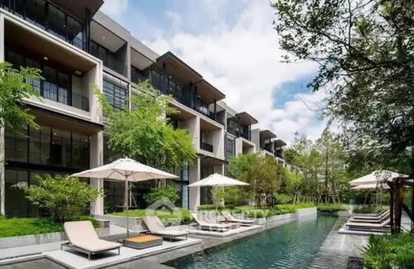 Luxurious modern apartment complex with poolside relaxation area and lush greenery.