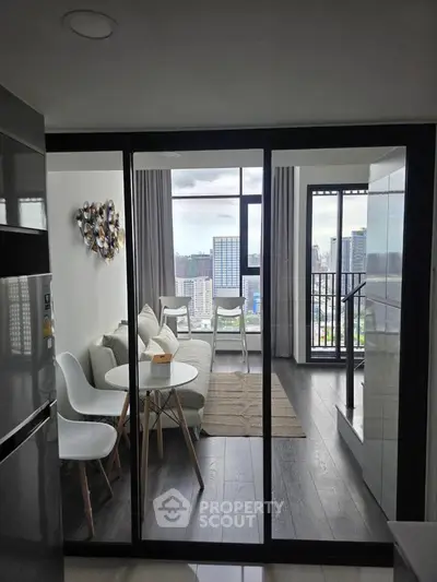 Modern living room with balcony and city view, featuring sleek furniture and floor-to-ceiling windows.