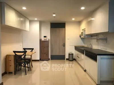 Modern kitchen with sleek cabinetry and dining area in open layout apartment