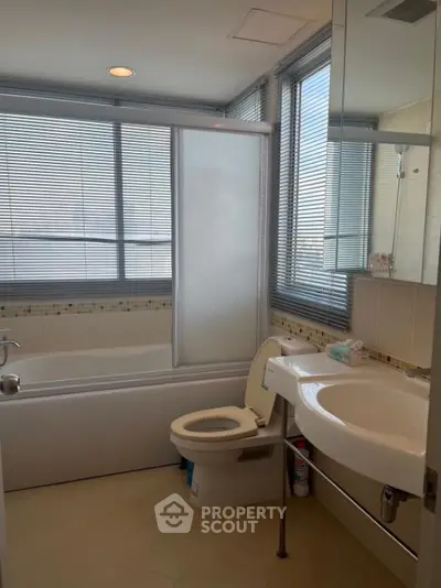 Modern bathroom with large windows and bathtub in a bright apartment.