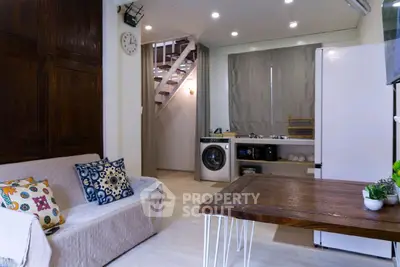 Charming living room with cozy sofa, modern kitchen, and washing machine in open layout.