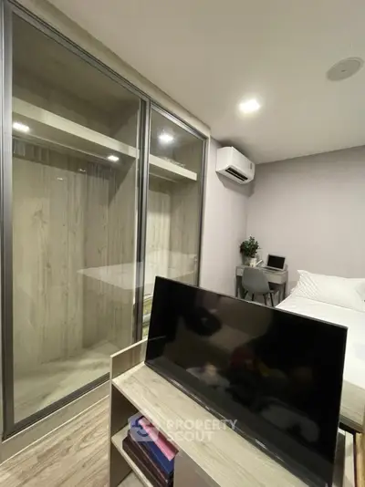 Modern bedroom with sleek wardrobe and mounted TV, ideal for urban living.