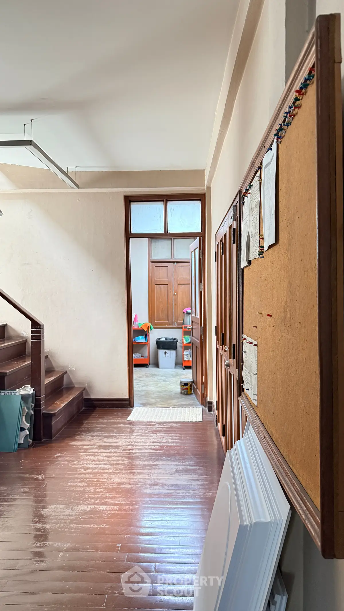Spacious hallway with wooden floors and staircase leading to a bright room