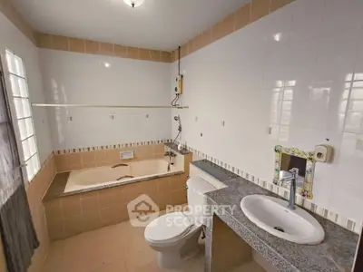 Spacious bathroom with bathtub and modern fixtures in a well-lit setting.