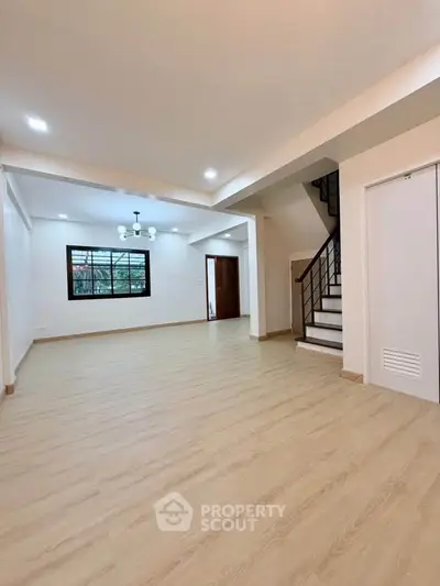 Spacious open-plan living room with modern staircase and elegant lighting.