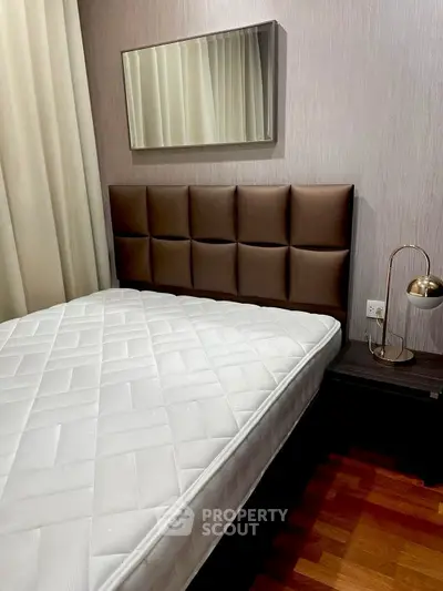 Cozy bedroom with stylish headboard and elegant bedside lamp, perfect for relaxation.