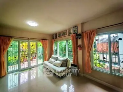 Spacious living room with large windows and garden view, perfect for relaxation and natural light.
