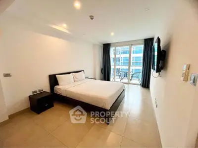 Spacious bedroom with modern furnishings and balcony view in a luxury apartment.