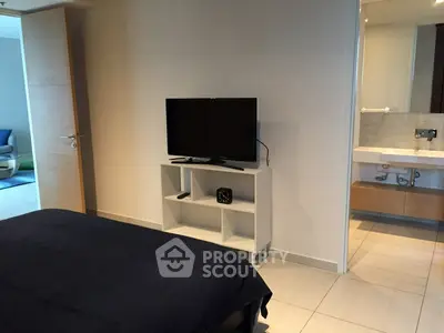 Modern bedroom with TV and ensuite bathroom in stylish apartment