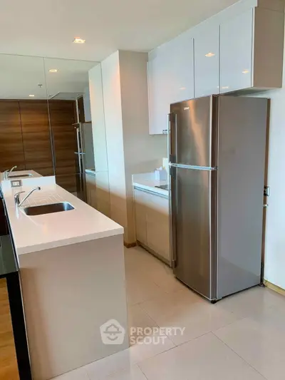 Modern kitchen with sleek design, stainless steel fridge, and ample counter space.