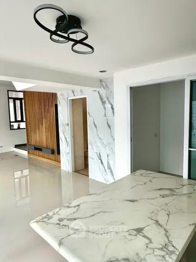 Modern open layout with marble accents and stylish lighting in a spacious living area.