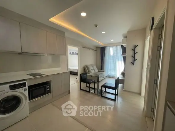 Modern open-plan living room with kitchen, featuring sleek cabinetry and natural light.