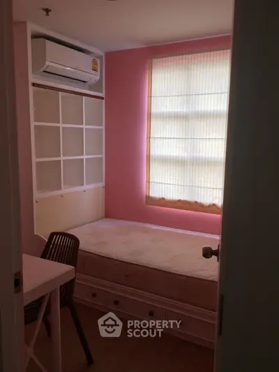 Cozy small bedroom with pink walls, single bed, and air conditioning unit.