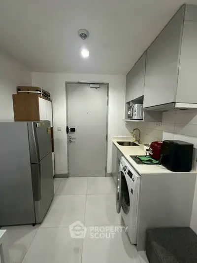 Modern compact kitchen with washing machine and sleek appliances in urban apartment.