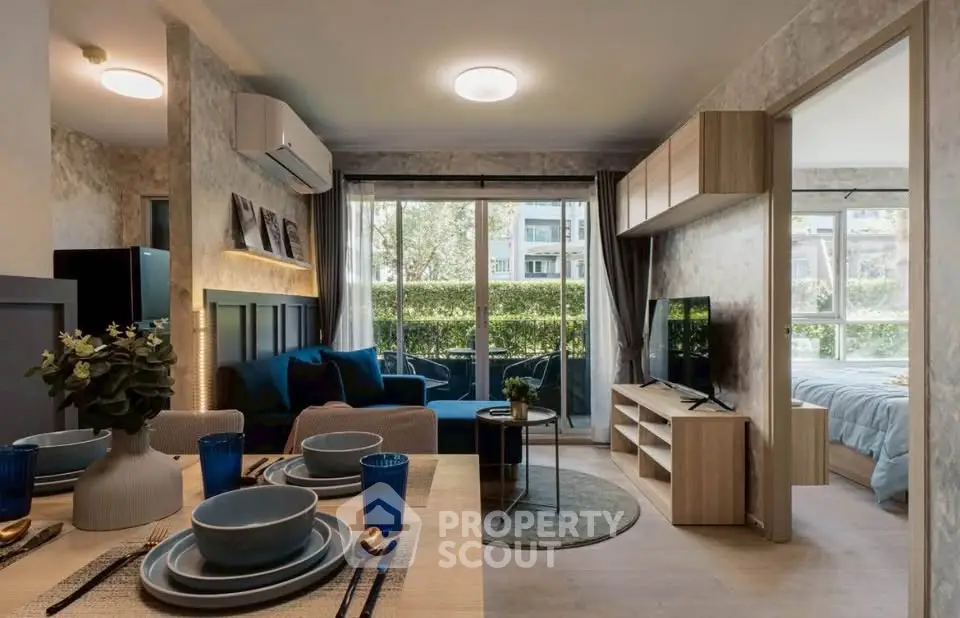 Modern open-plan living room with dining area and bedroom view, featuring stylish decor and large windows.