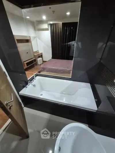 Modern bathroom with bathtub and view into stylish bedroom