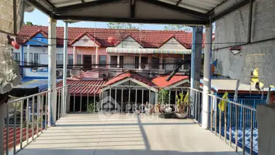 Charming residential view from a covered balcony overlooking colorful townhouses with red roofs.