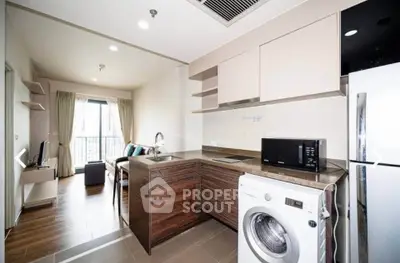 Modern open-layout kitchen with washing machine and cozy living area in stylish apartment.