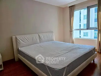 Spacious bedroom with large window and modern bed frame, offering natural light and comfort.