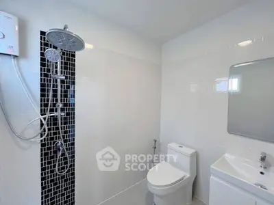 Modern bathroom with sleek shower and white fixtures in a contemporary home.