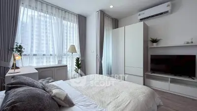 Modern bedroom with large windows, stylish decor, and natural light in a high-rise apartment.