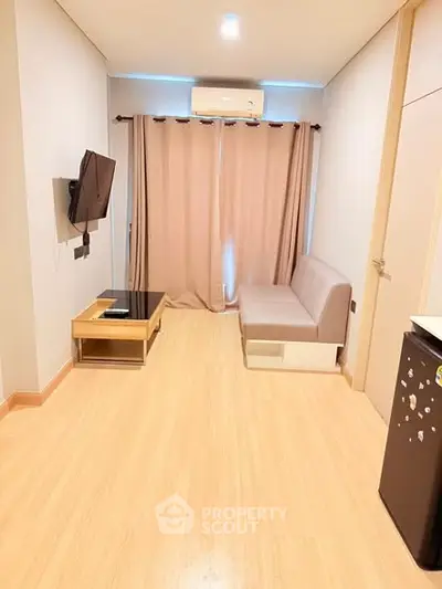 Modern living room with wooden flooring, wall-mounted TV, and cozy sofa in a stylish apartment.