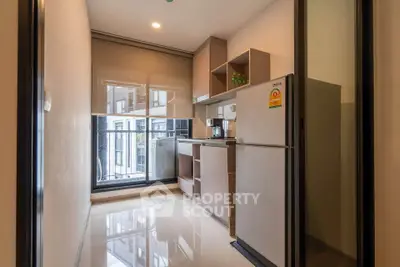 Modern kitchen with sleek cabinets and large window in a stylish apartment.