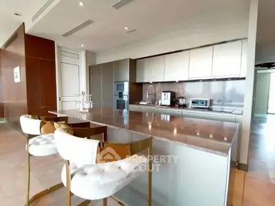 Luxurious modern kitchen with sleek design and high-end appliances, featuring a spacious island and elegant bar stools.