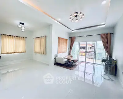 Spacious living room with modern lighting and large windows opening to a balcony.
