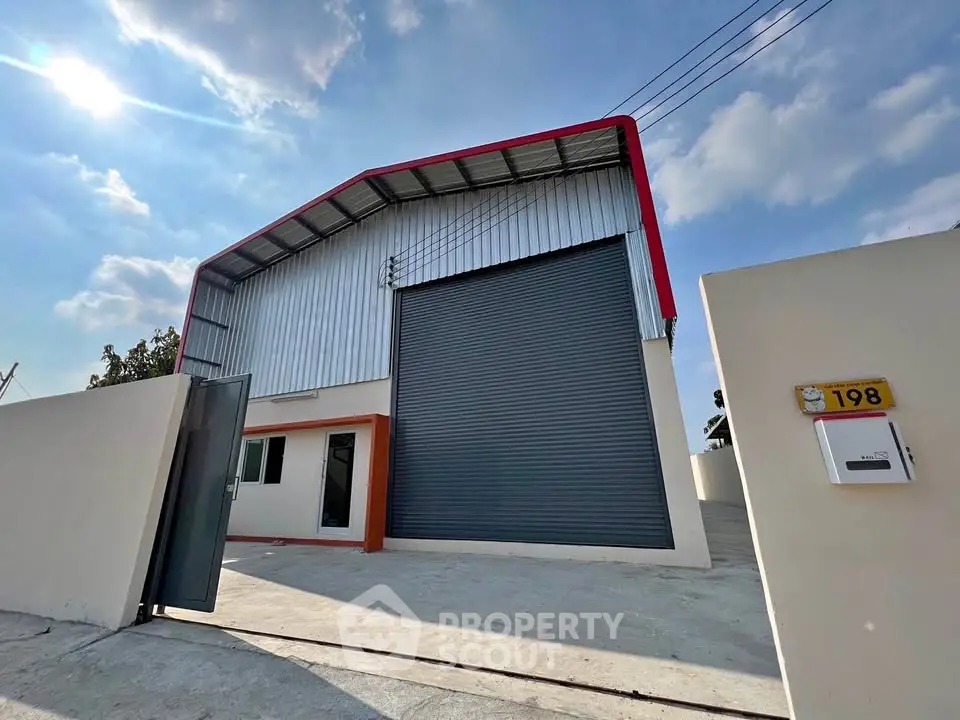 Modern industrial warehouse with large roller door and secure gated entrance.