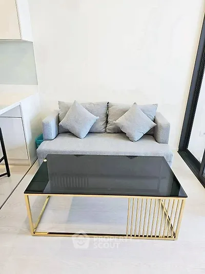 Modern living room with sleek gray sofa and stylish glass coffee table in a bright interior.