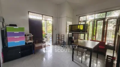 Spacious living room with large windows and garden view, featuring modern furniture and natural light.