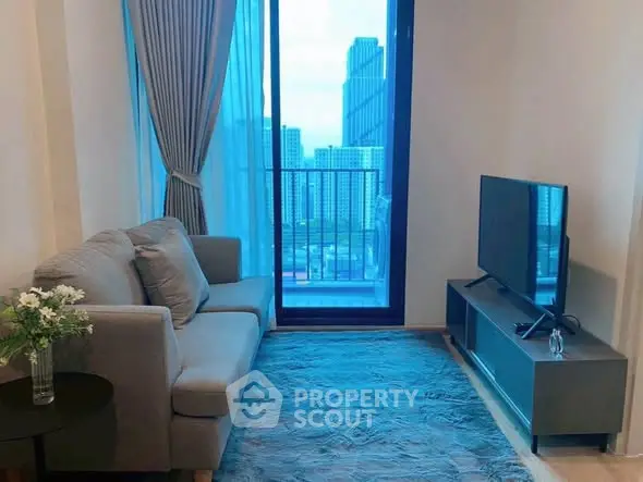 Cozy living room with city view, featuring a modern sofa and flat-screen TV, perfect for relaxation.